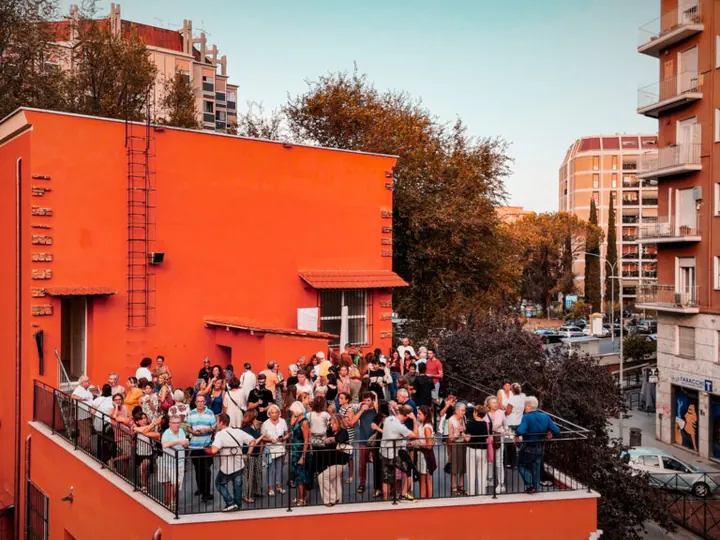 La terrazza arancione di EtiopiaLab in Viale Etiopia piena di persone durante un evento al tramonto